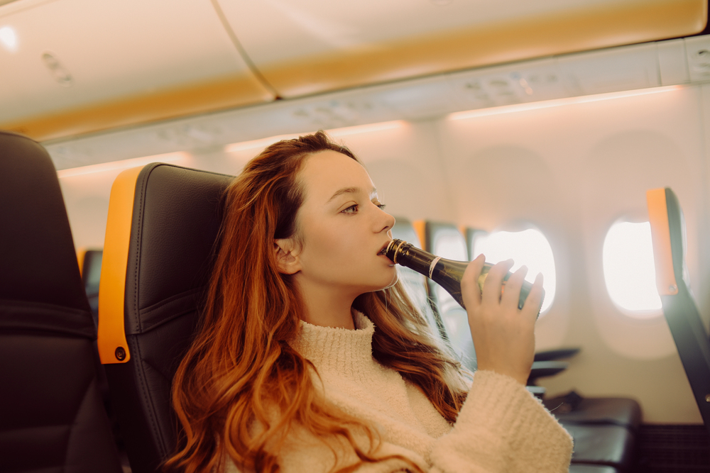 girl drinking alcohol in plane